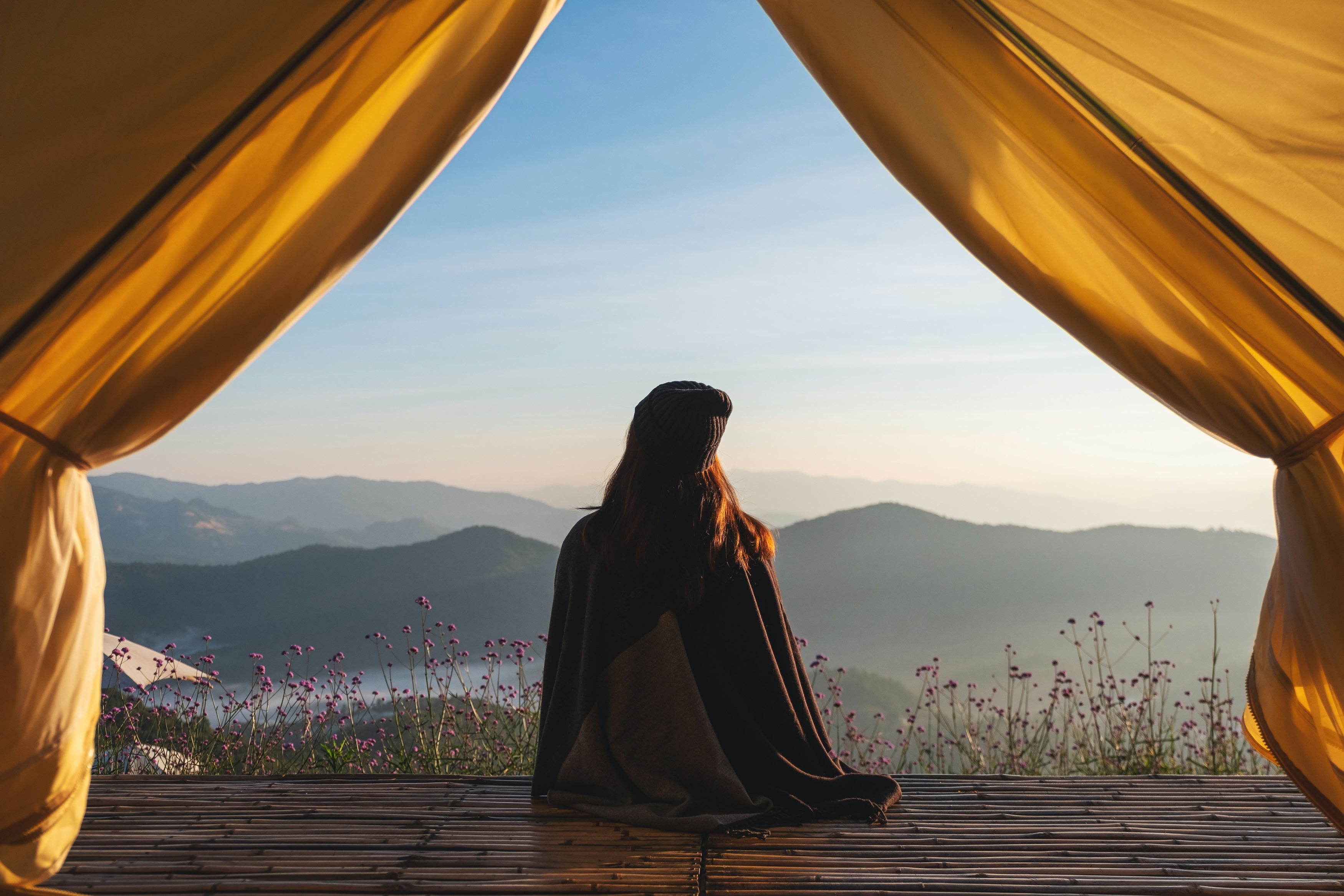 A person sitting on a platform overlooking a beautiful vista of rolling mountains