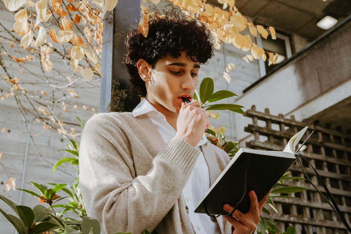 A person holding a journal with fall leaves visible in the background