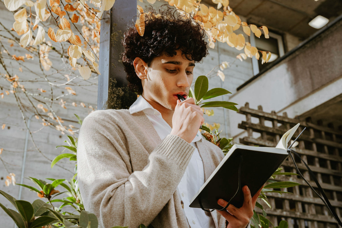 A person holding a journal with fall leaves visible in the background