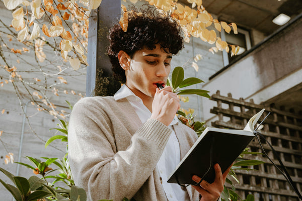 A person holding a journal with fall leaves visible in the background