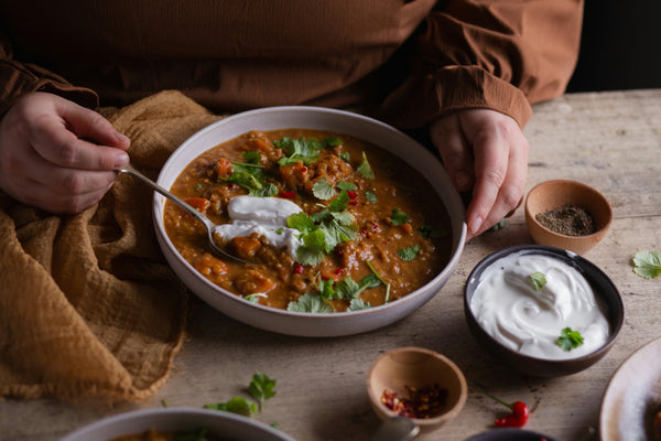 Two hands holding a bowl of stew