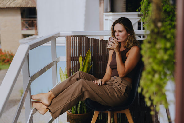 A woman sitting on a balcony sipping on a beverage