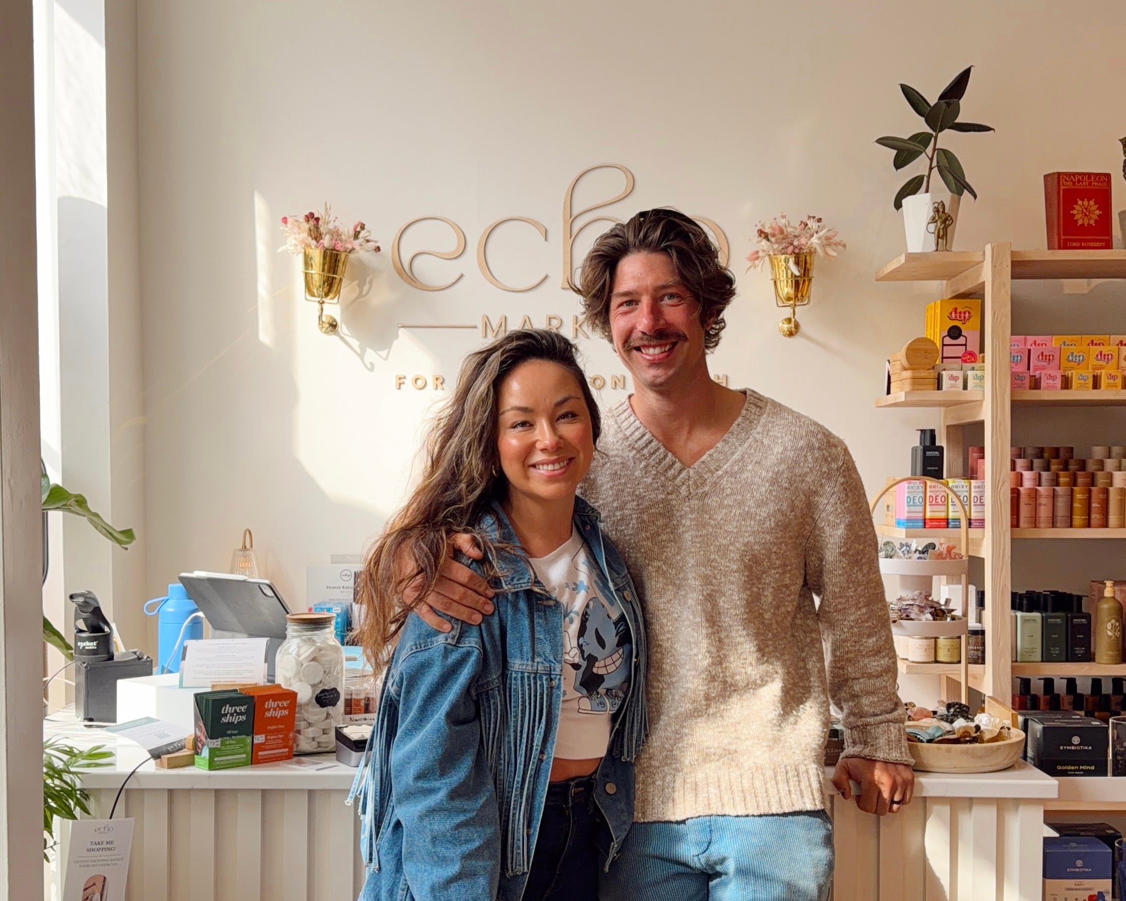 Will and Victoria Hurd, smiling in front of the Echo Market Woodstock front desk