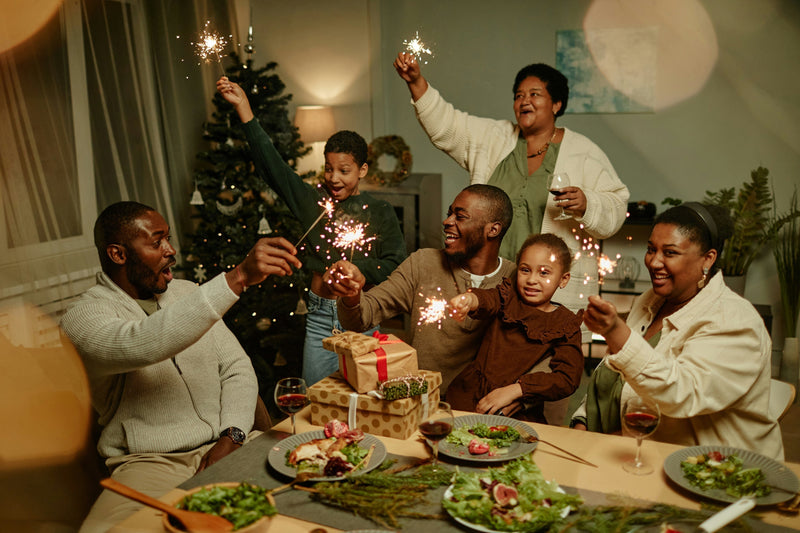 A multi-generational family, sitting around a dinner table, celebrating Christmas with sparklers