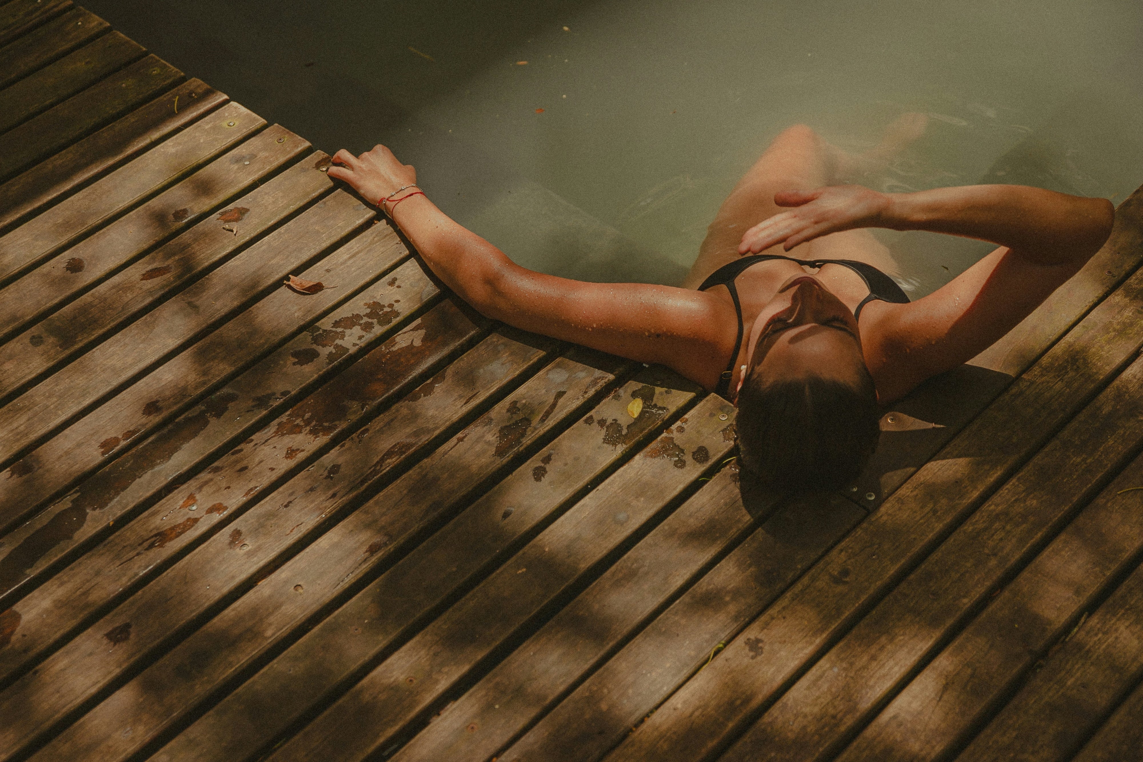 A woman laying back in a pool with their hand shading their eyes