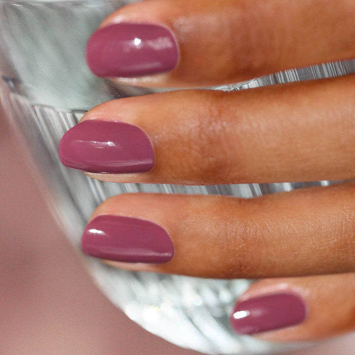Close-up of a hand with Victoria Plum nail polish on a blurred background