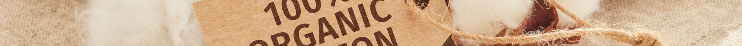 A wooden sign with "100% Organic Cotton" printed on it, set on natural fabric