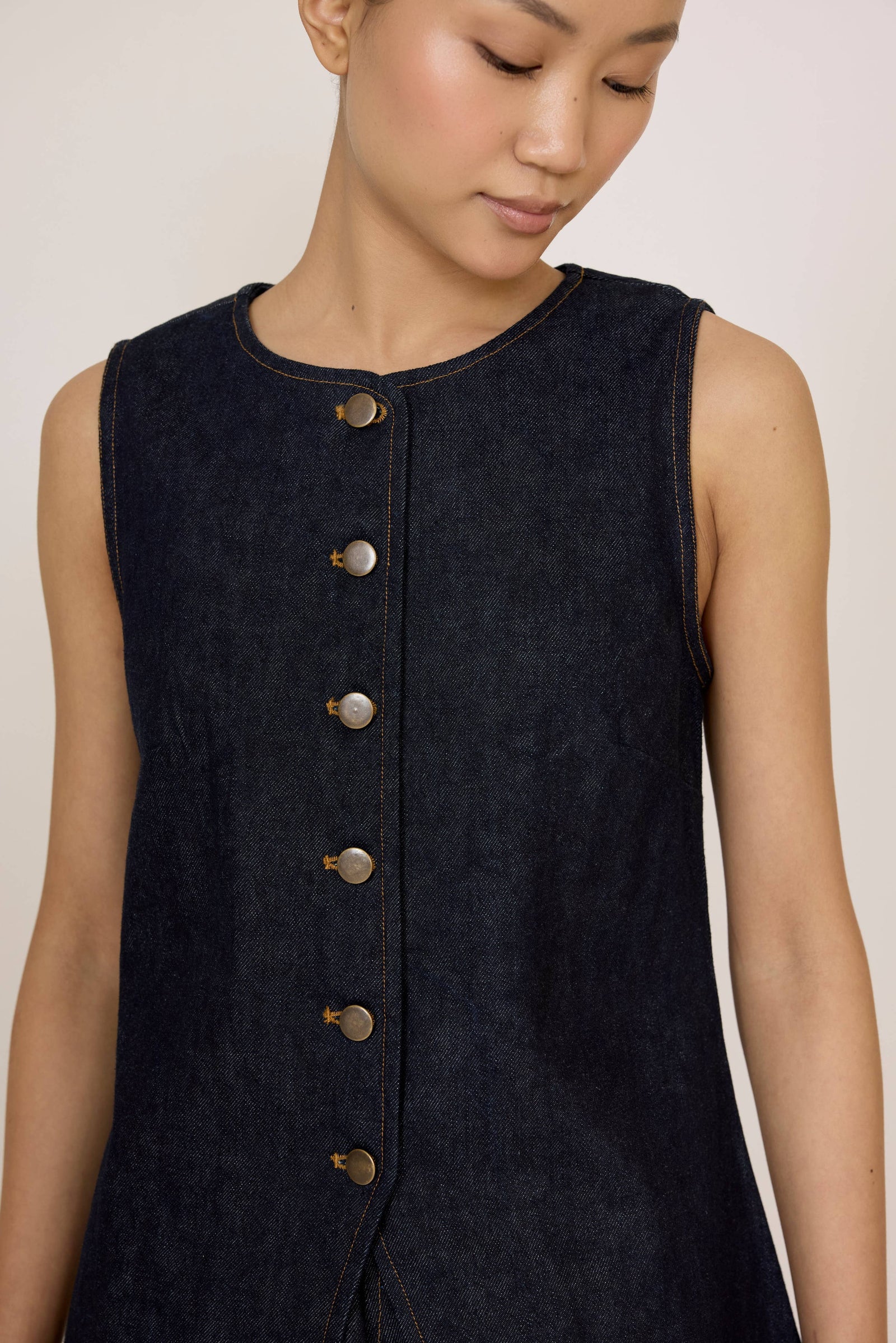 Woman wearing a Laude Longline Vest in Dark Indigo over a plain background