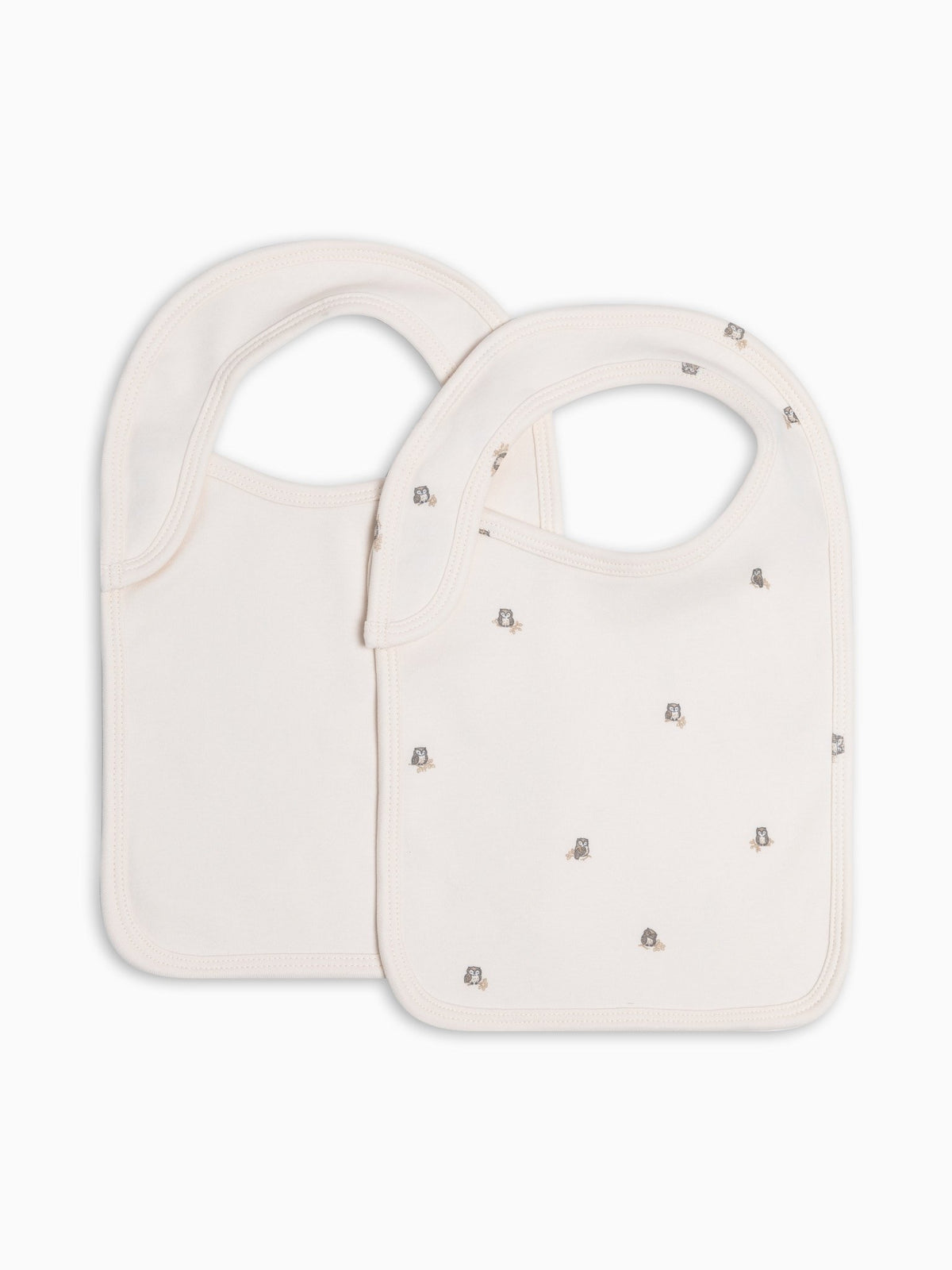Two cream-colored baby bibs, one with small owl details, displayed on a clean white background.