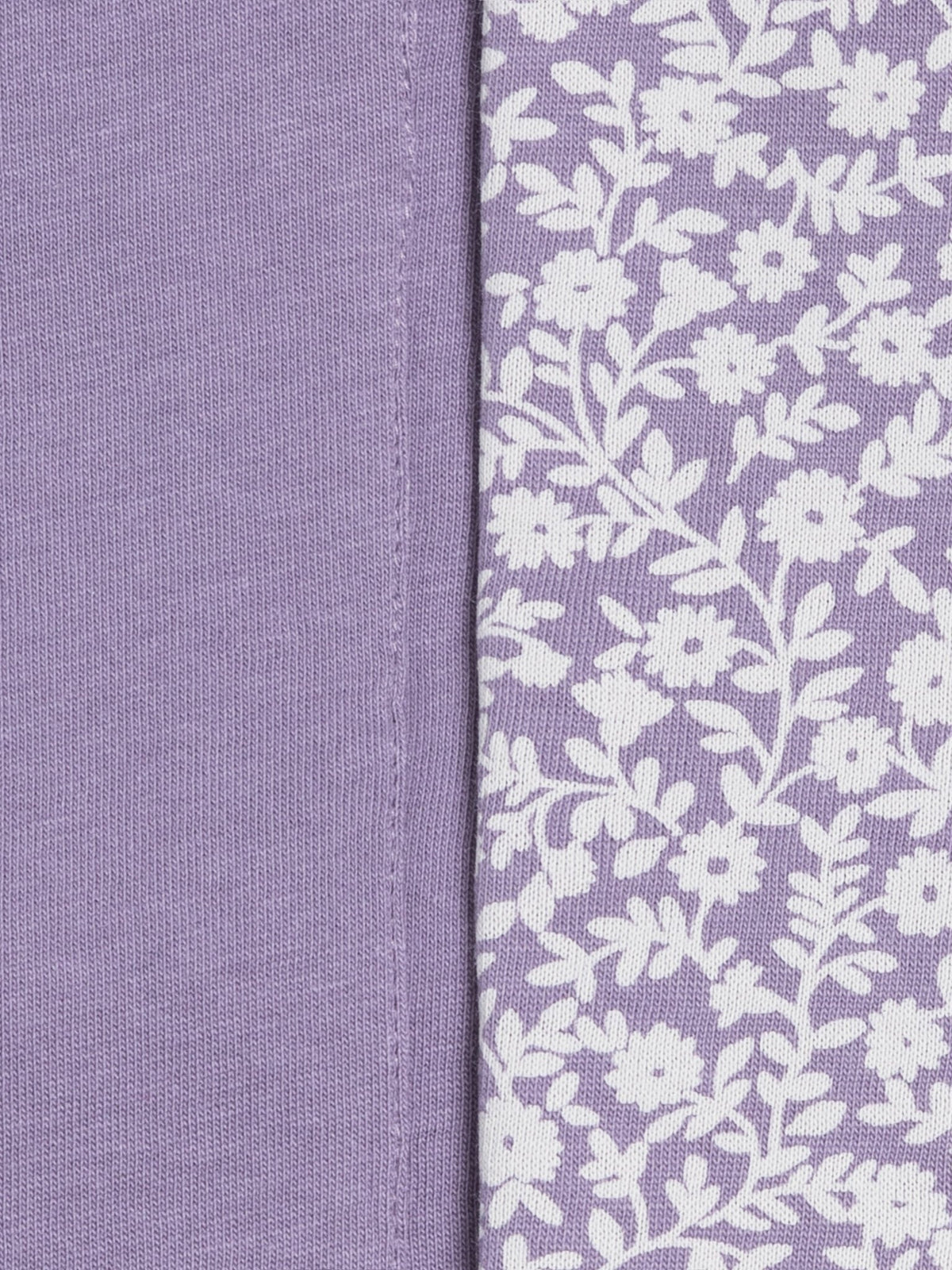 Close-up of a lavender fabric product showing two sides: one solid lavender side and one side with a white floral vine pattern on lavender.