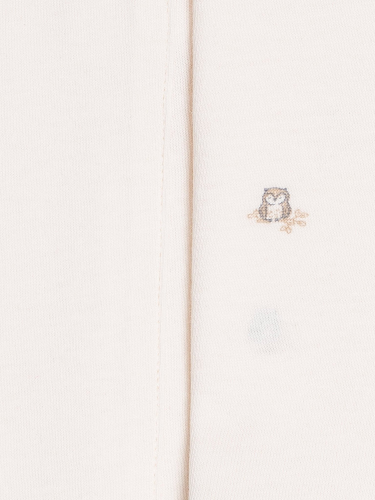 Close-up of two colored organics burp clothes in ivory, one with owl print 