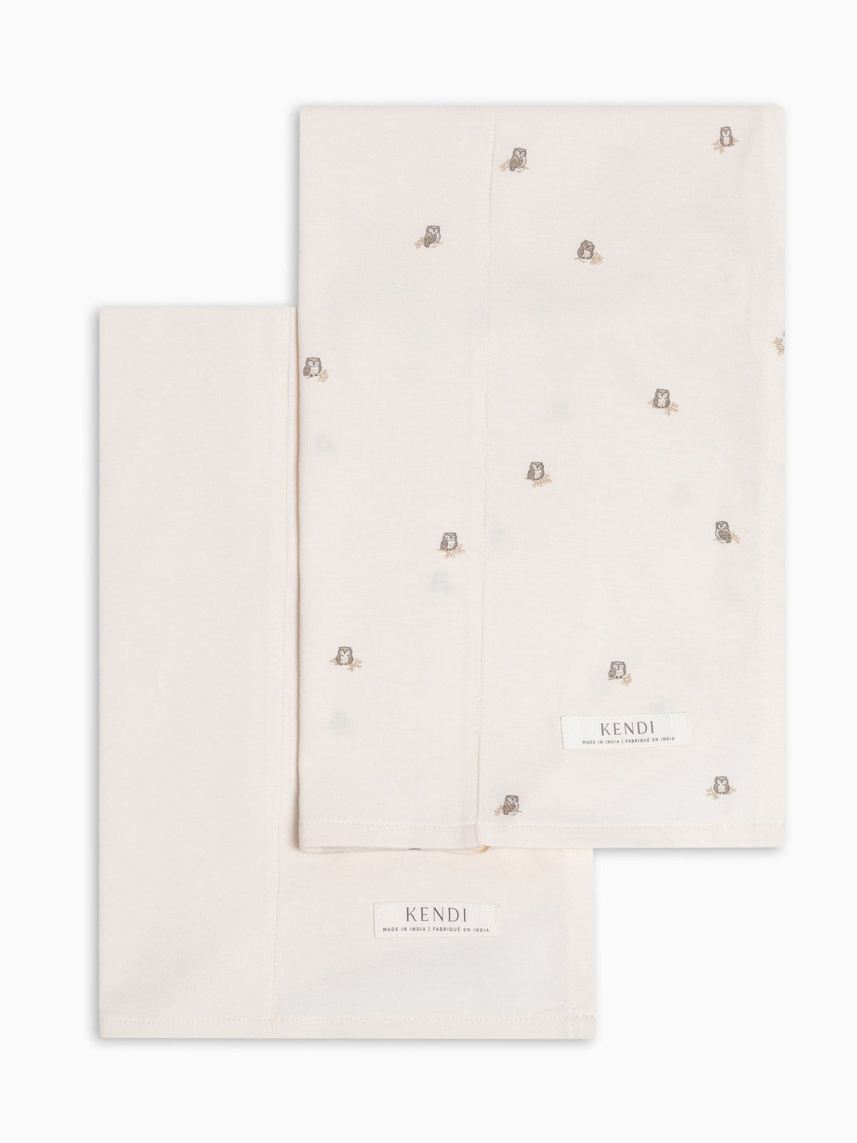 Two colored organics burp clothes in ivory, one with owl print on a white background.