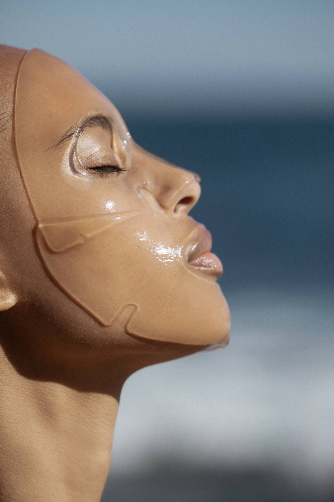 Close-up of a person wearing a clear face mask against a blurred natural background