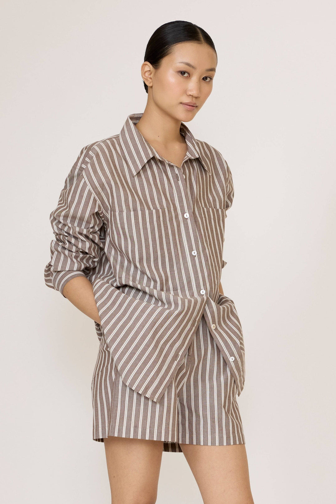 Woman wearing a Laude Everything Shirt in Acorn Stripe and matching shorts set on a plain background