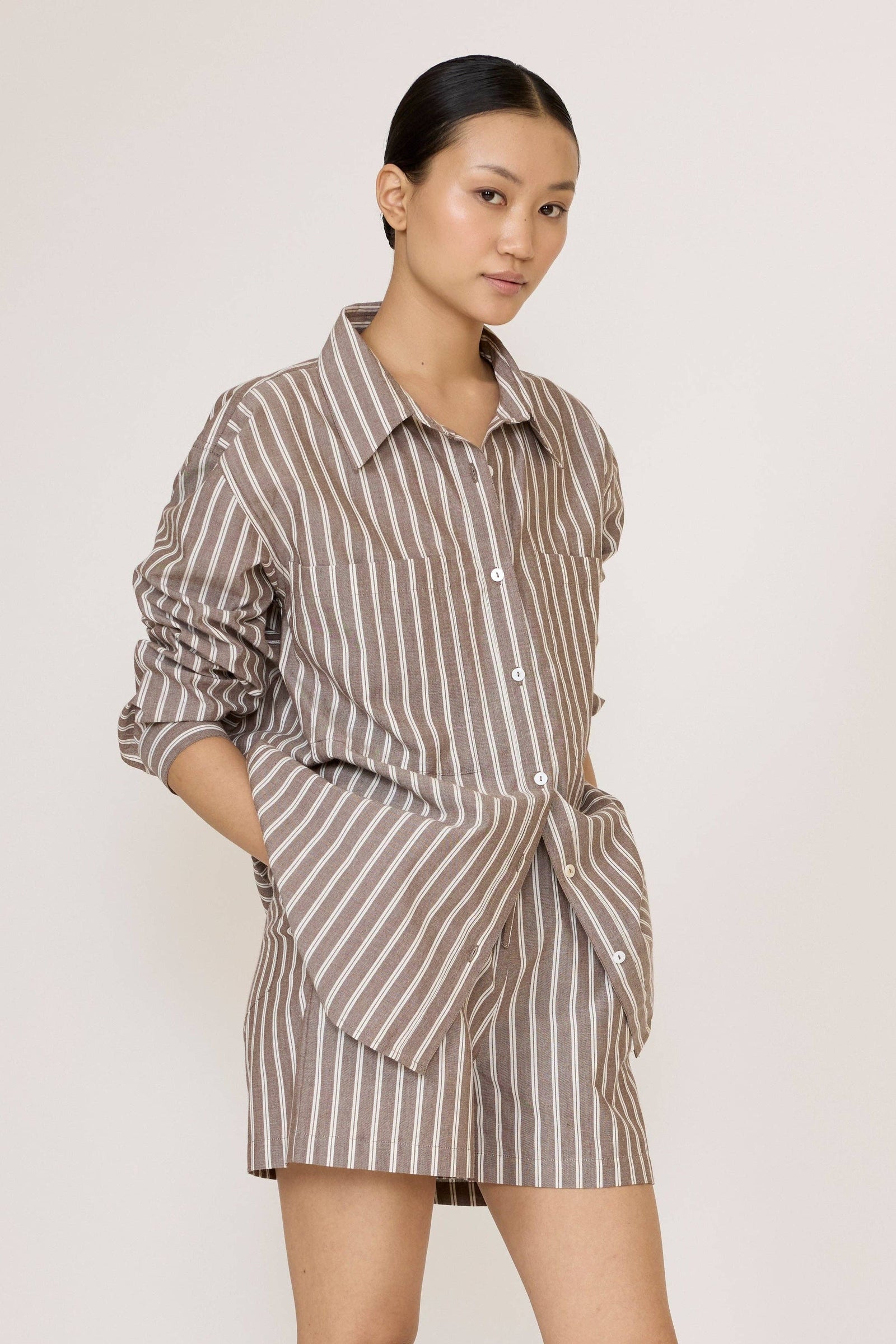 Woman wearing a Laude Everything Shirt in Acorn Stripe and matching shorts set on a plain background