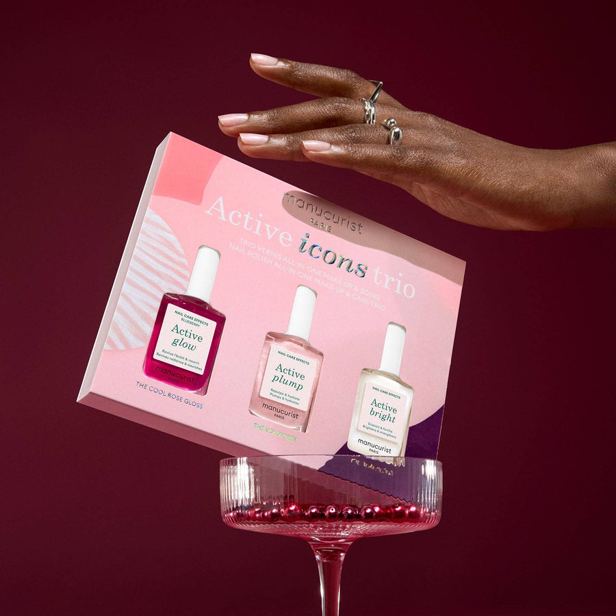 Hand holding a box of 'Active Icons' Nail polish  set with a red background