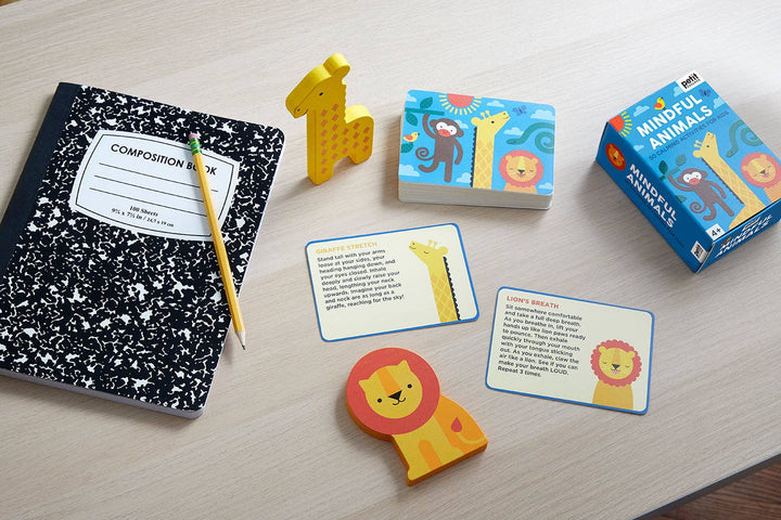 Educational materials including a composition book, pencils, and animal-themed cards on a wooden surface.