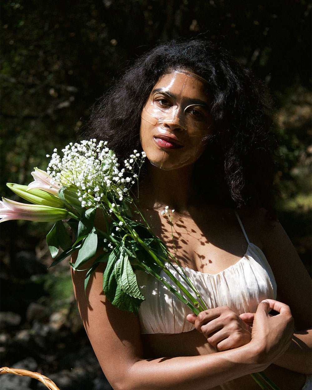 Woman holding a bouquet of flowers wearing a face mask in a natural setting