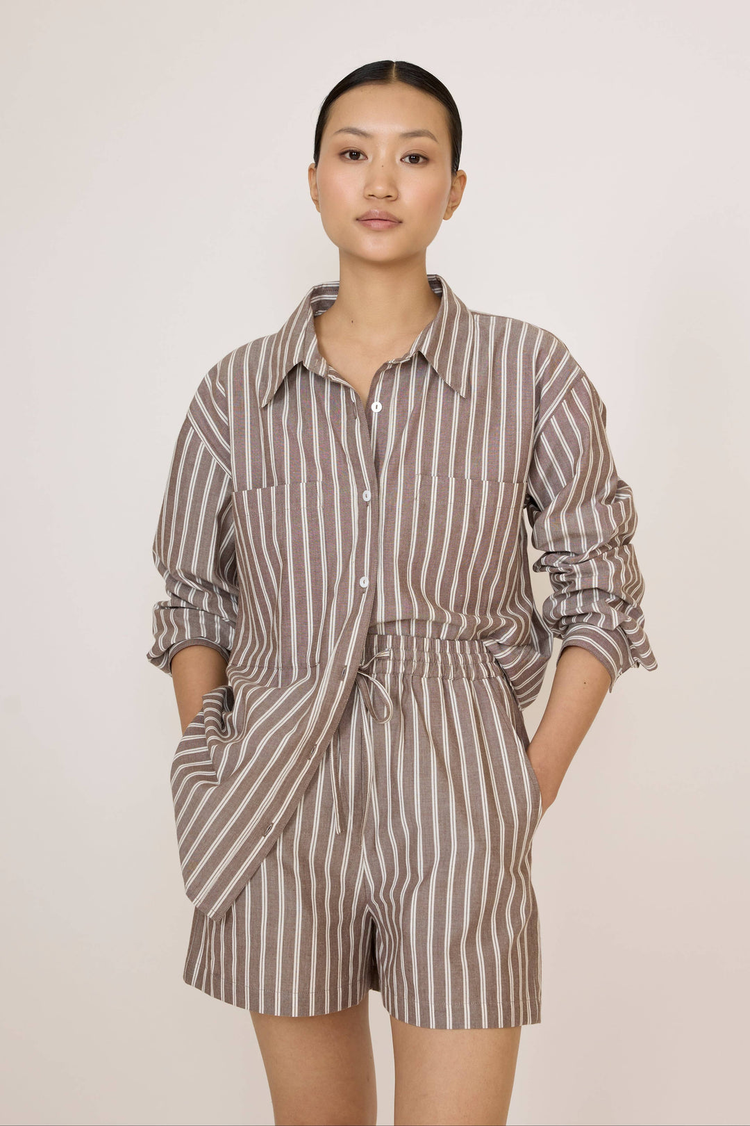 Woman wearing a Laude Everything Shirt in Acorn Stripe and matching shorts set on a plain background