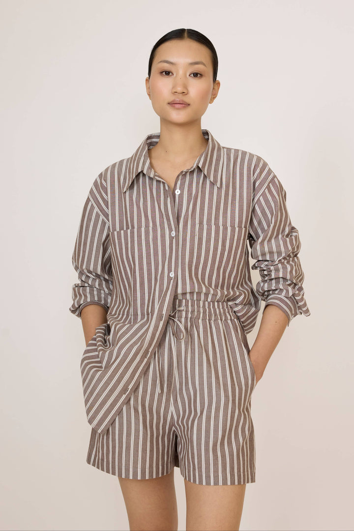 Woman wearing a Laude Everything Shirt in Acorn Stripe and matching shorts set on a plain background