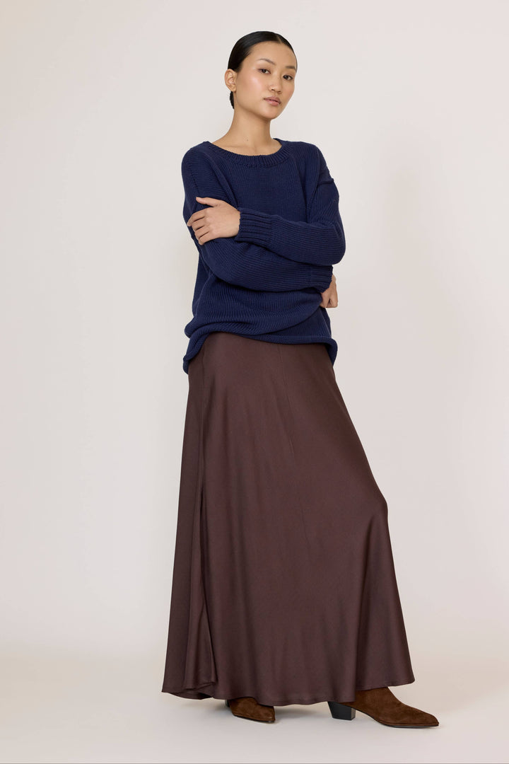 Woman wearing a Navy top and Bias Maxi Skirt in Chocolate Brown on a white background