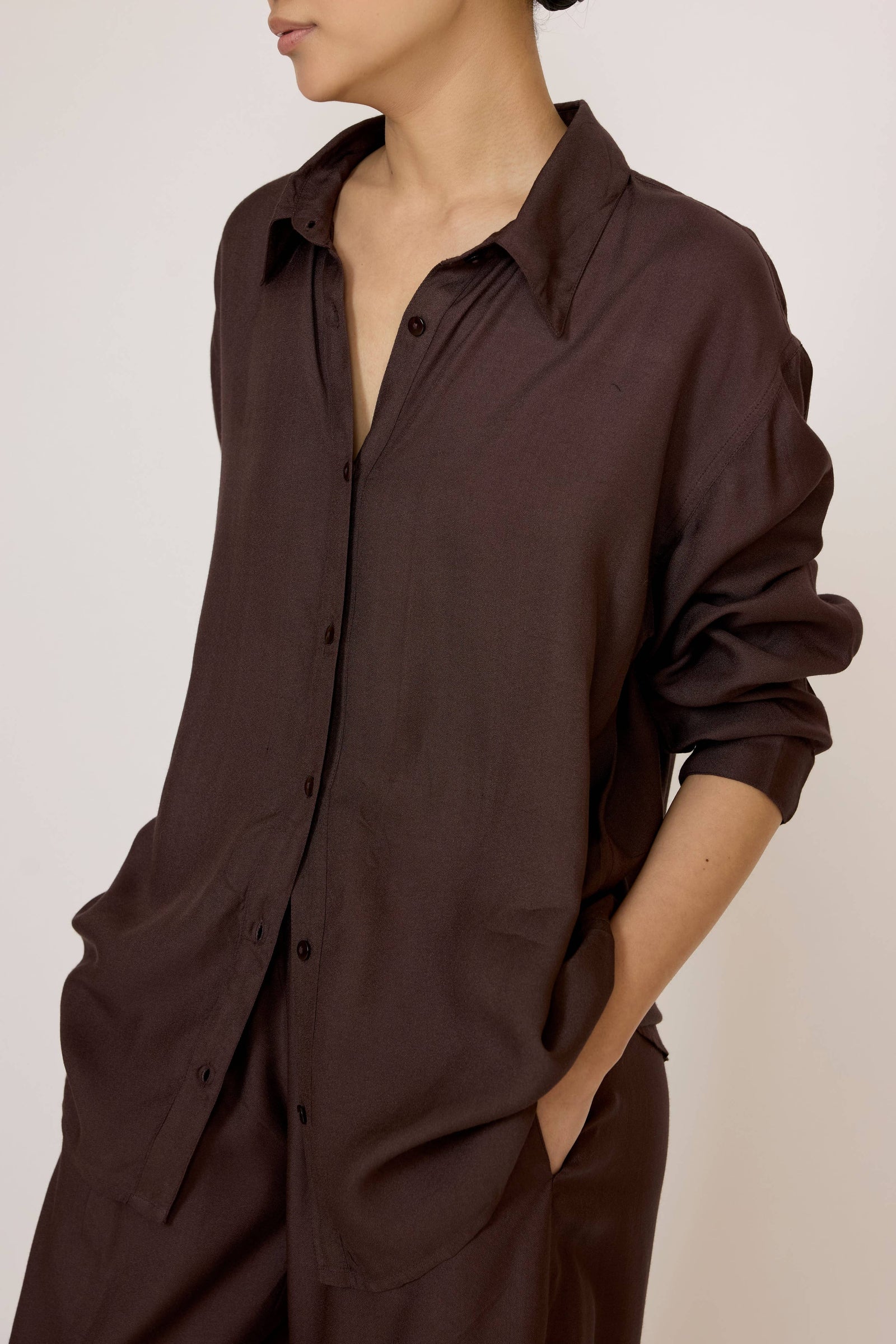 Woman wearing a Laude Everything Shirt in Chocolate Brown with a neutral background