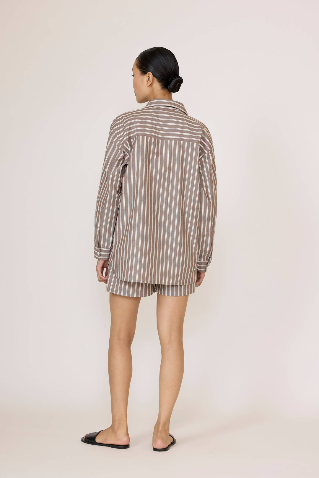 Woman wearing a Laude Everything Shirt in Acorn Stripe and matching shorts set on a plain background