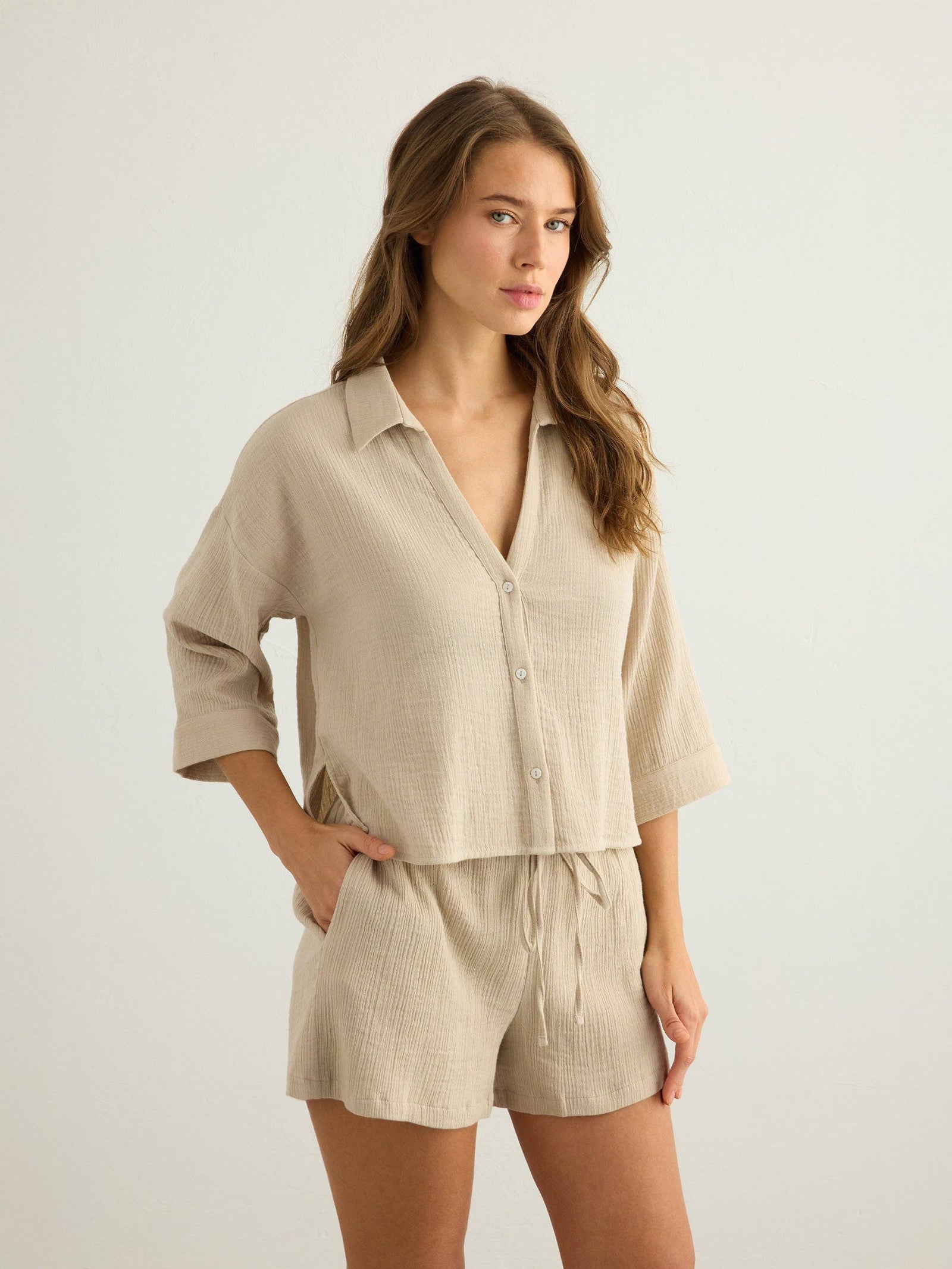 Woman wearing a Handloom Aura oatmeal button-up shirt and shorts on a plain background