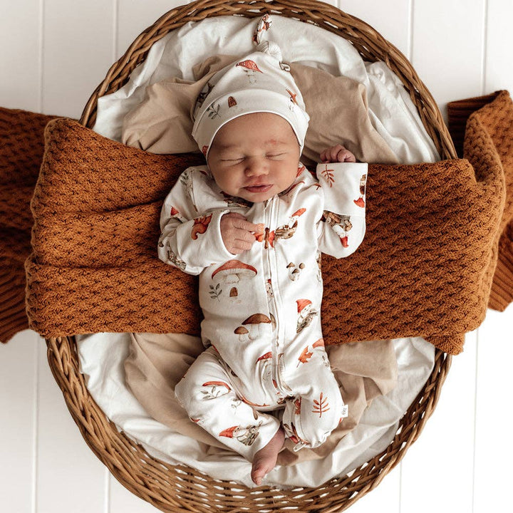 Newborn baby in a wicker basket wearing Snuggle Hunny&