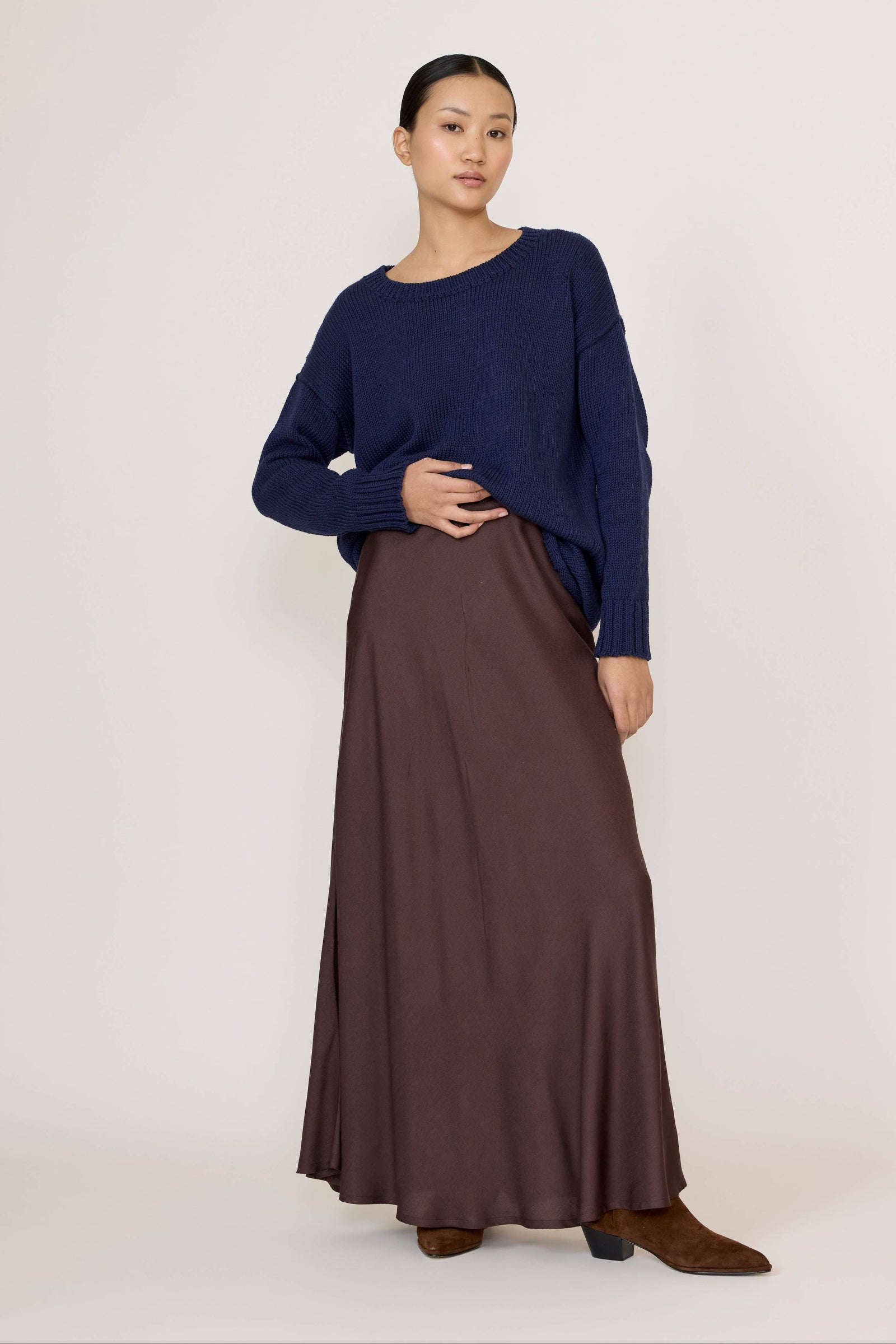 Woman wearing a Navy top and Bias Maxi Skirt in Chocolate Brown on a white background