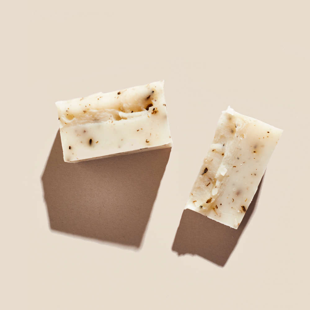 Two bars of soap with specks on a beige background