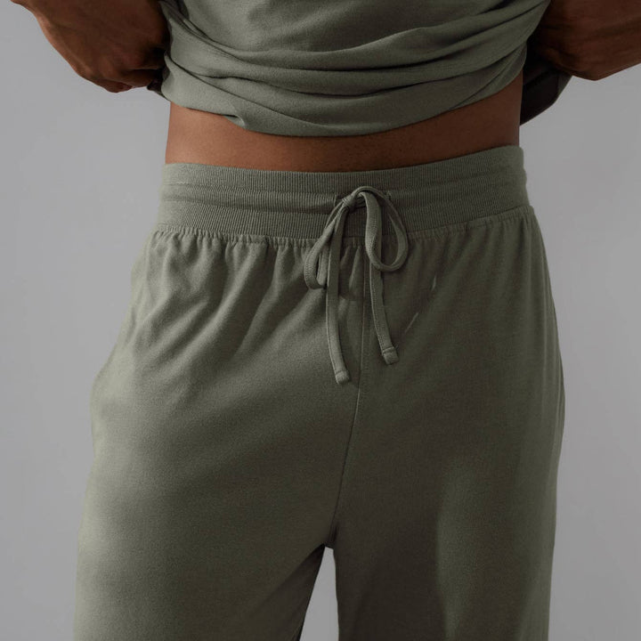 Person wearing olive green pants with a plain background