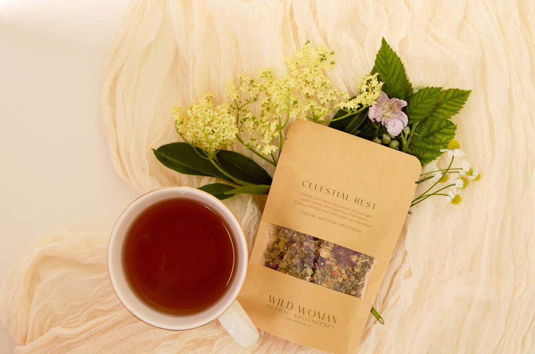 Tea cup with a package of Wild Woman tea on a textured surface with flowers.