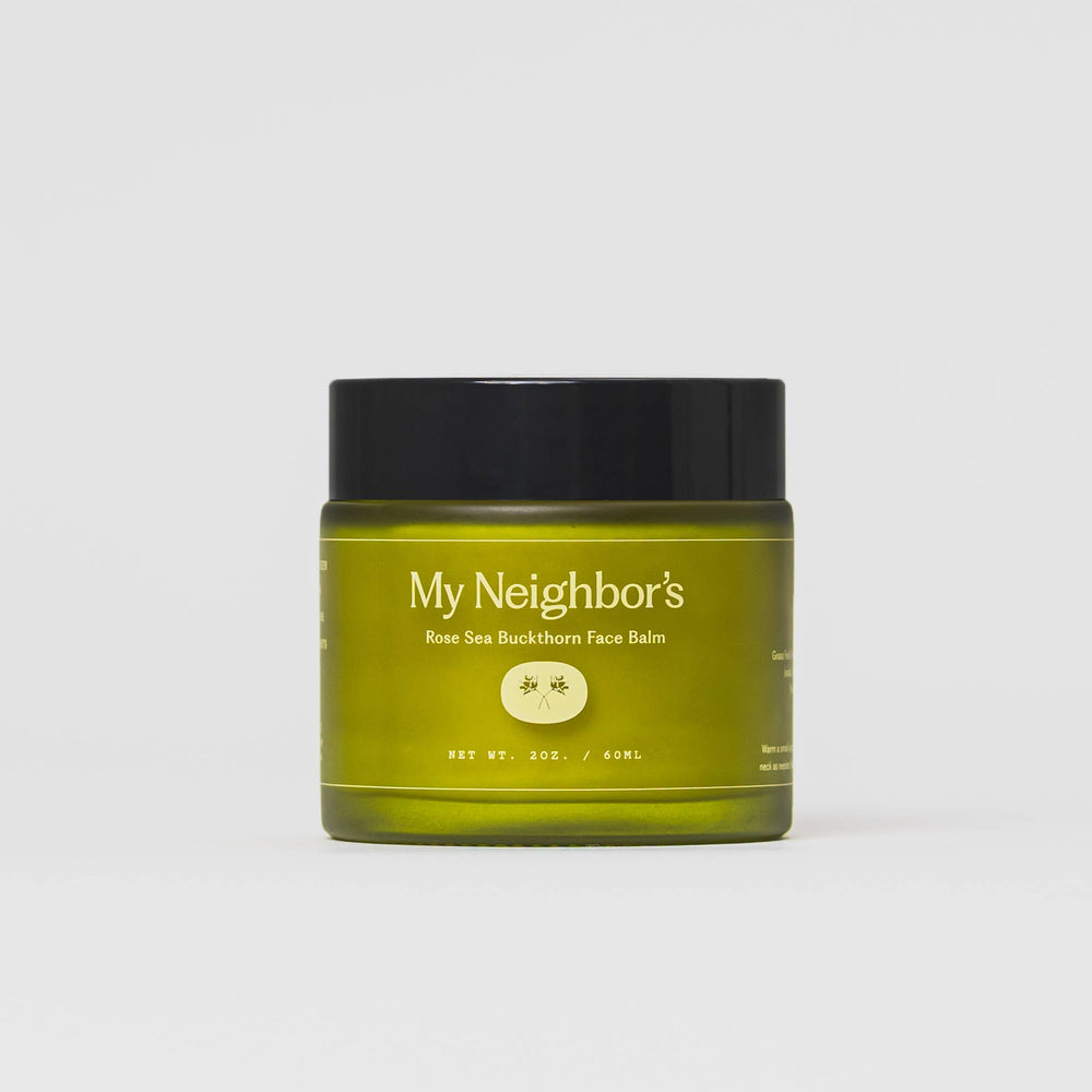 Green jar of 'My Neighbor's' face balm with black lid on a white background