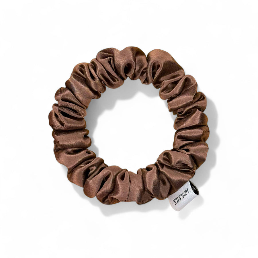 Brown silk scrunchie with a brand label on a white background