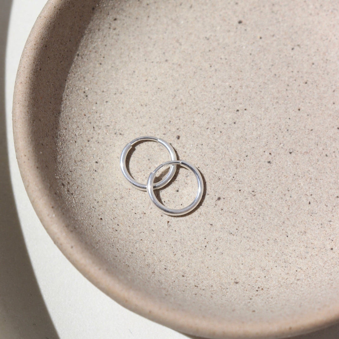 Two silver rings on a textured beige ceramic plate