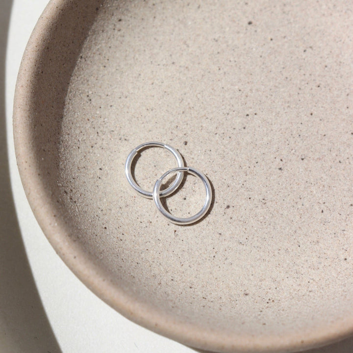 Two silver rings on a textured beige ceramic plate