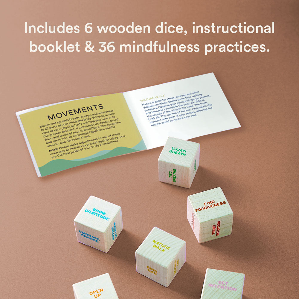 Set of wooden dice with mindfulness prompts and an instructional booklet on a brown background