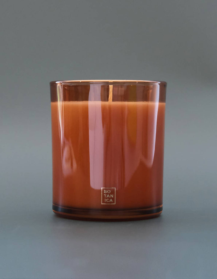 Candle in a glass container with a logo on a gray background
