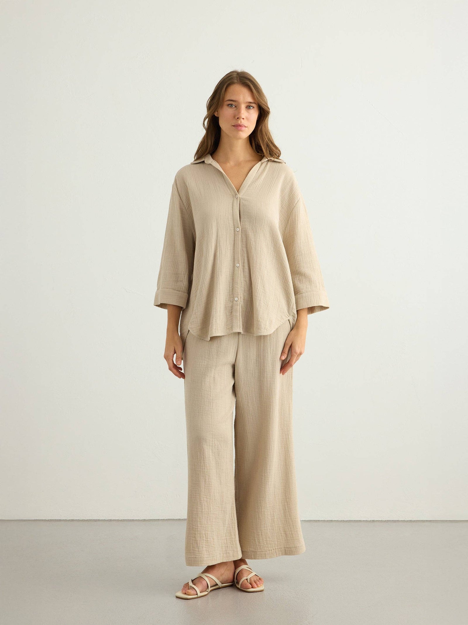 Woman wearing The Handloom's Aura Maxi Shirt  in Oatmeal with wide-leg pants against a white background