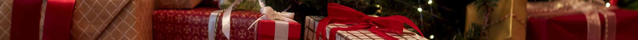 Close-up of red and white and gold-wrapped presents under a tree with decorative elements.