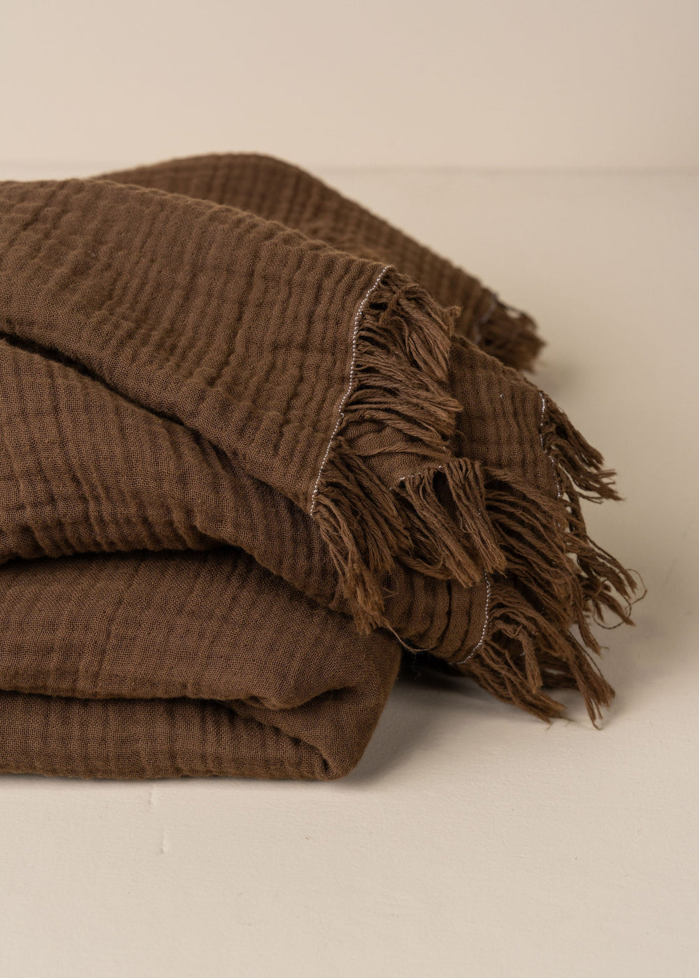 Folded brown textured blanket on a beige background