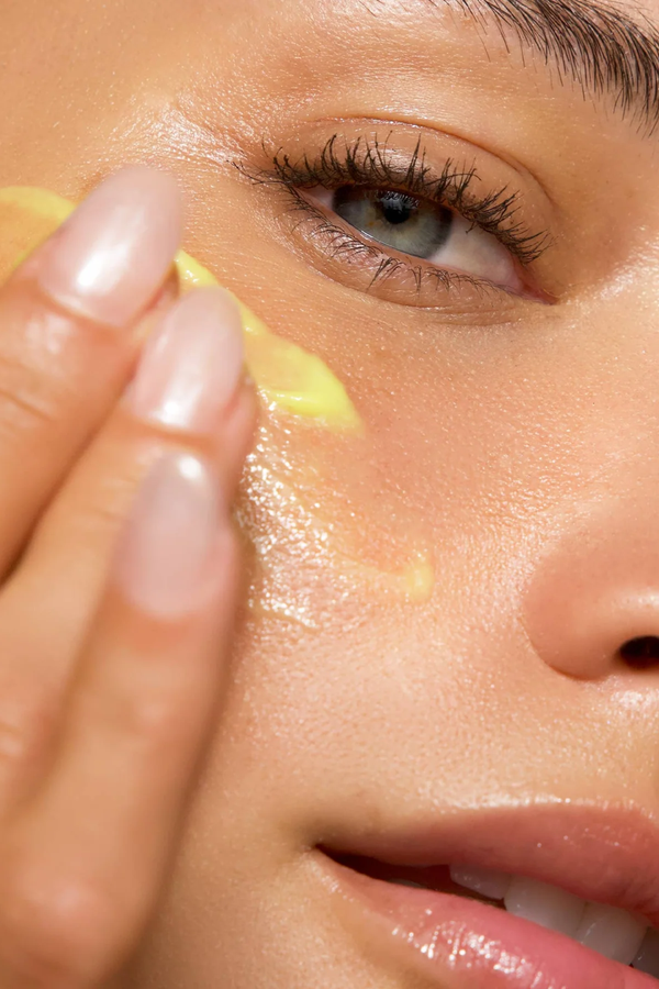 Close-up of a person applying a yellow cream to their face