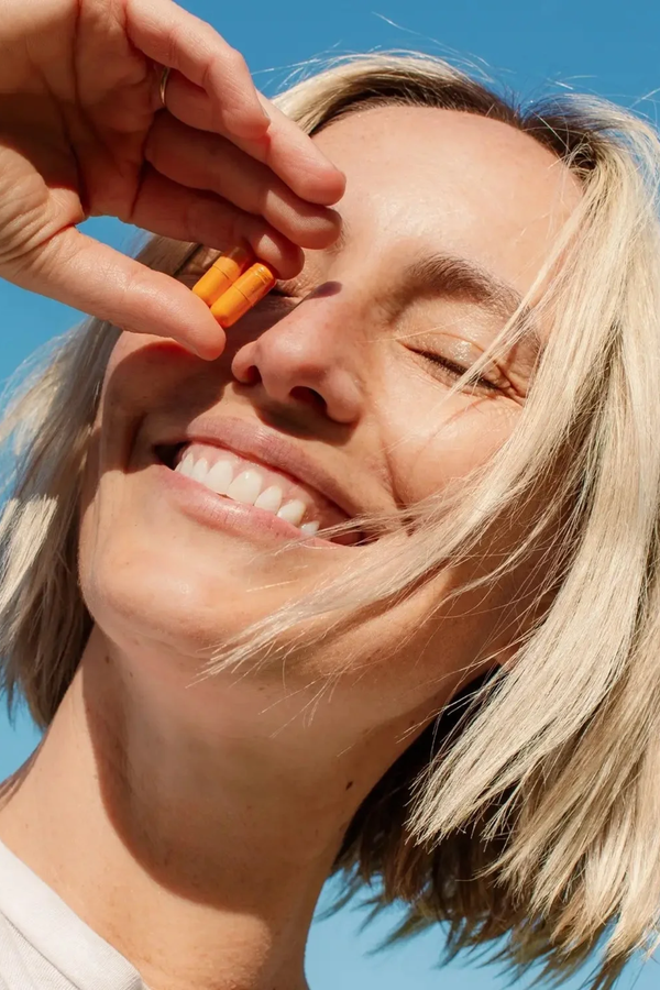 Person holding a small object near their eye against a clear blue sky