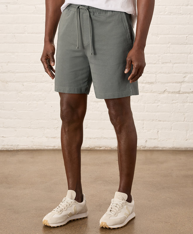 Pact Stash French Terry Short in Castor Green View with Sneakers.