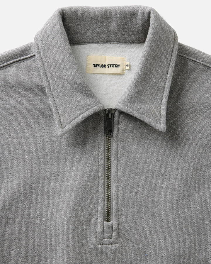 Close-up of a heather gray quarter-zip sweatshirt collar with a visible neck label reading Taylor Stitch.