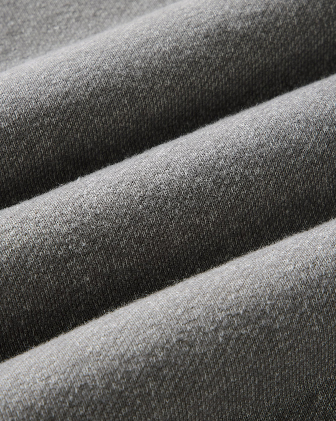 Close-up of draped gray knit fabric with a fine ribbed texture and soft folds.