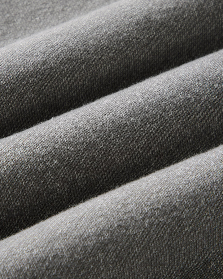 Close-up of draped gray knit fabric with a fine ribbed texture and soft folds.