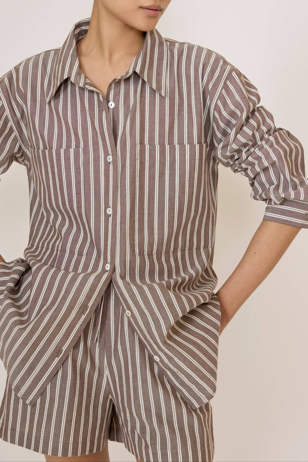 Woman wearing a Laude Everything Shirt in Acorn Stripe and matching shorts set on a plain background