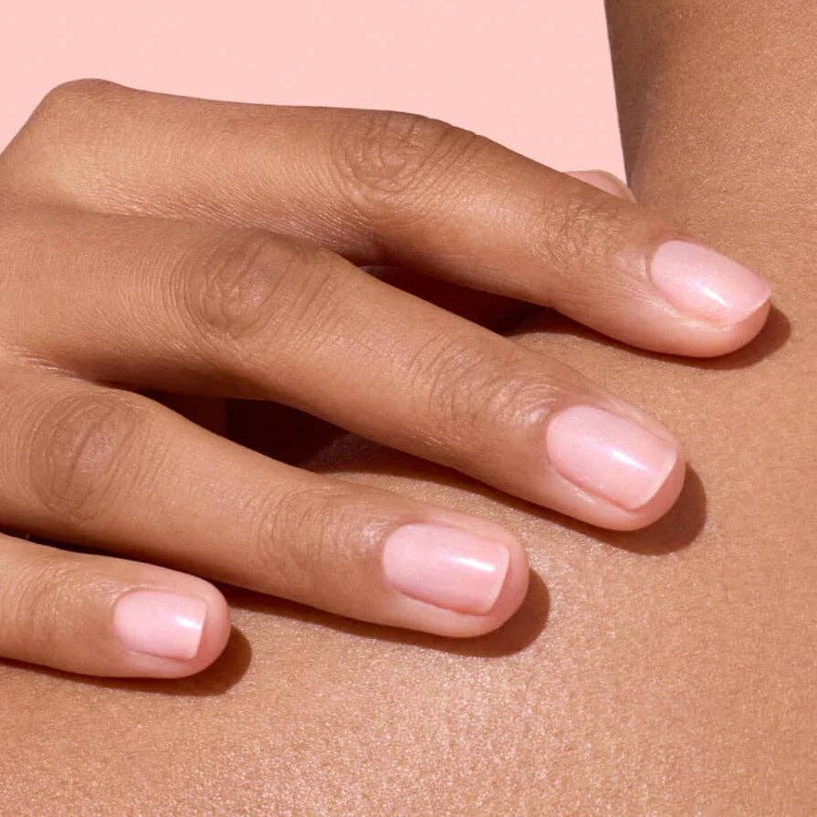 Close-up of a hand with light pink nail polish on a matching background